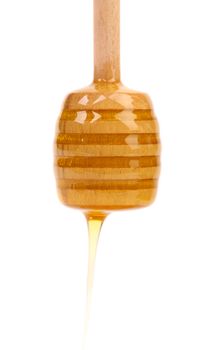 Honey dripping from a wooden honey dipper on white background