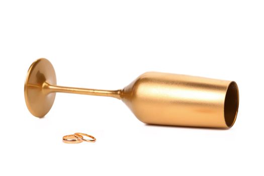 Wedding rings and golden champage glass. White background.