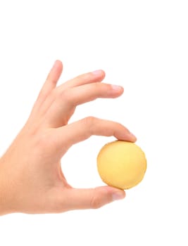 Hand holds traditional French yellow macaron against a white background.