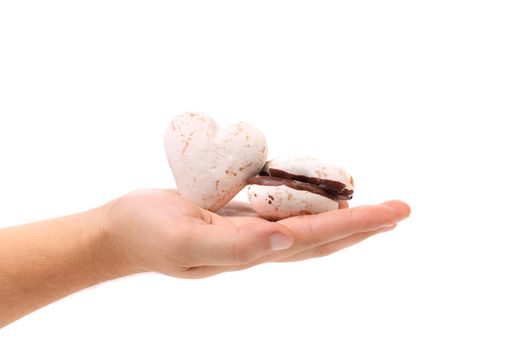 Hand holds heart shape chocolate meringues. White background.