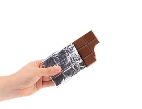 Hand holds dark chocolate bar in foil. White background.