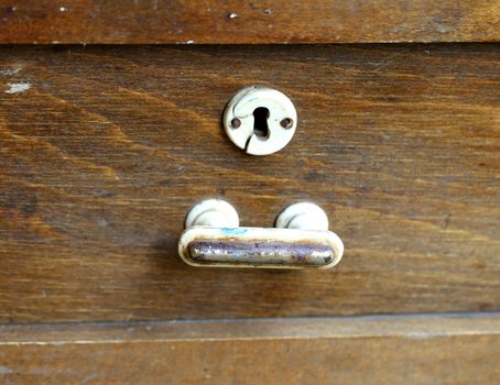 Metal handle and keyhole of an old wooden table. Close up.