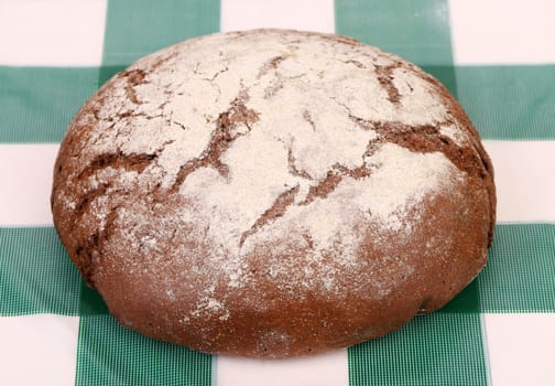 Freshly baked traditional bread on check tablecloth. Close up.