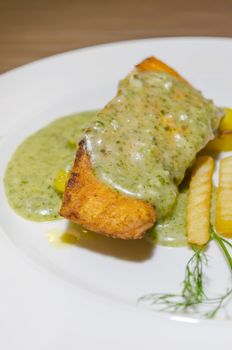 close up grilled  salmon served with green sauce and french fries 
