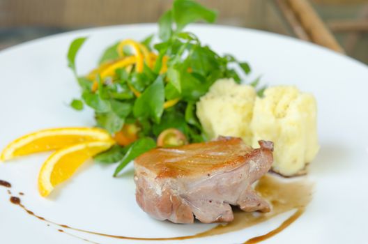 close up roasted duck breast  served with mashed potatoes and orange , fresh salad  on dish