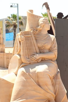 sculpture of a woman with a musical instrument out of the sand