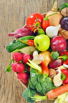 Fresh vegetables and fruits in basket on wooden table