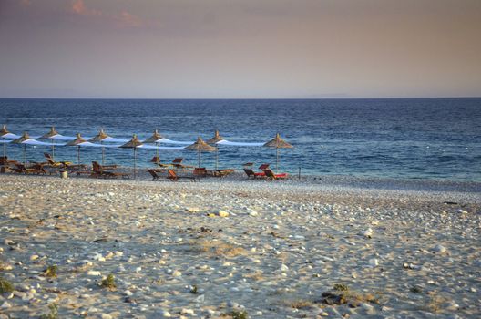 Recliners with umbrellas on a pebble beach.