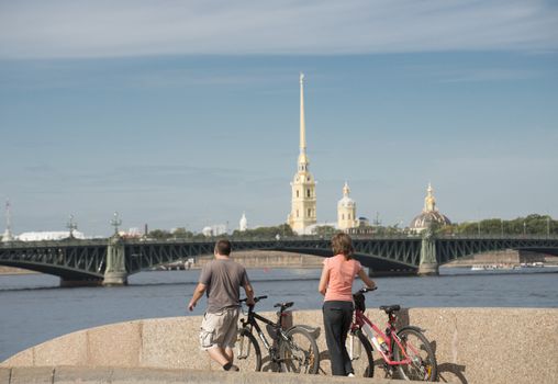 Two bicyclist in the Sankt Petersburg. On the backside view of Peter and Paul Cathedral.