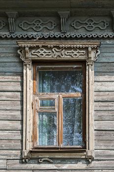 Old unpainted wooden window with carved architraves, Tutaev, Russia