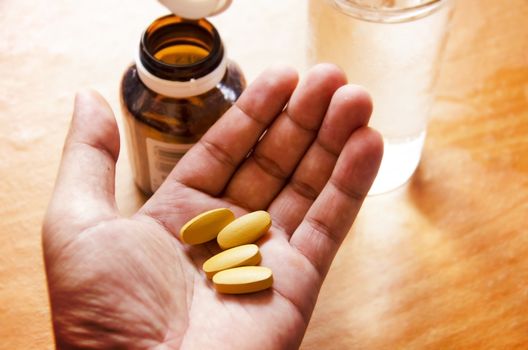 Pills spilling from a bottle into a hand.