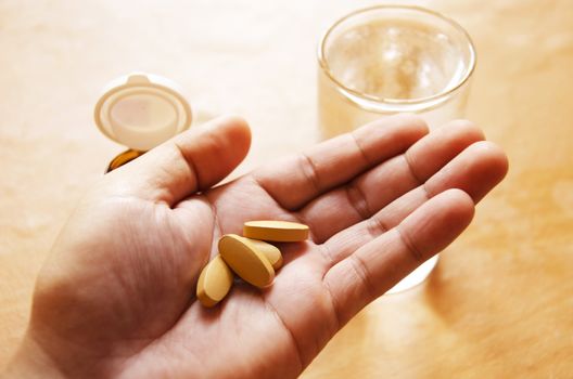 Pills spilling from a bottle into a hand.