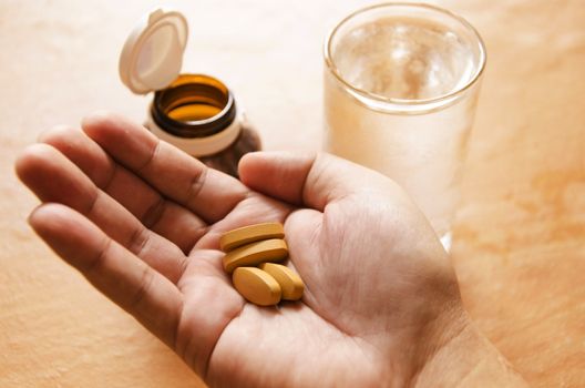 Hand holding yellow pills