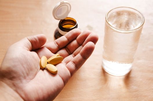 Pills spilling from a bottle into a hand.