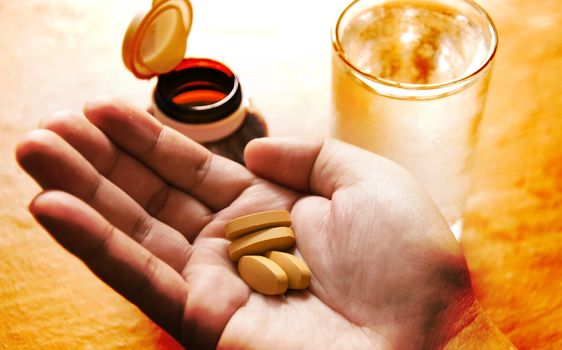Hand holding yellow pills