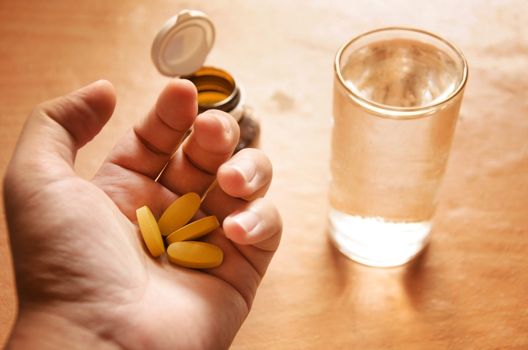 Hand holding yellow pills