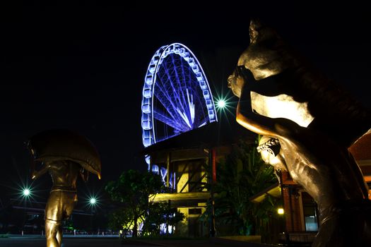 Bangkok at twilight in the dark of sky with ferris wheel background and foreground of the chinese labor statue
