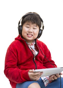 Vertical shot of a young Asian boy in red listening to music with a headphone isolated on white.