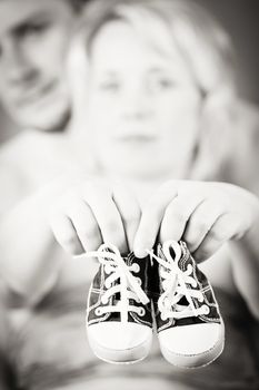 couple in love with a child's shoe and man tenderly holding her tummy with hand