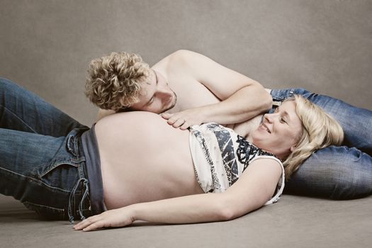 A loving young father laying his head on the swollen belly of his pregnant wife listening to the heart beats of his unborn baby