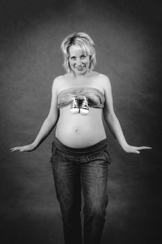 beautiful smiling pregnant woman with child boots on her tummy