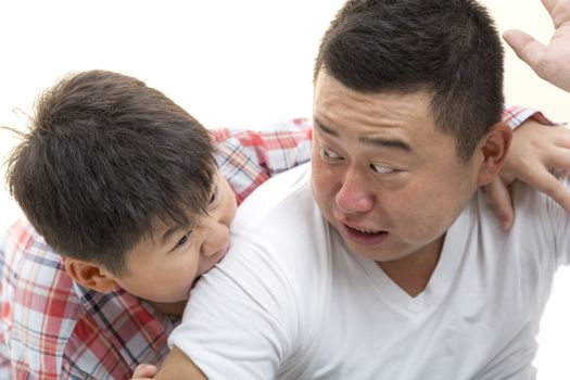 Asian son biting father shoulder while playing on isolated white backrgound