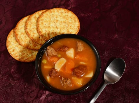 beef and vegetable soup with crackers in restaurant