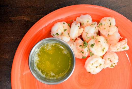 steamed shrimp with butter on orange plate and wooden table