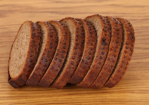 Sliced brown bread with coriander. Wooden background.