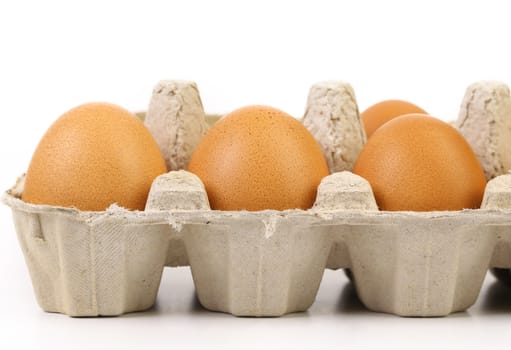 Four brown eggs in egg box. Isolated