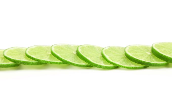 Slices of green lemon on a white background