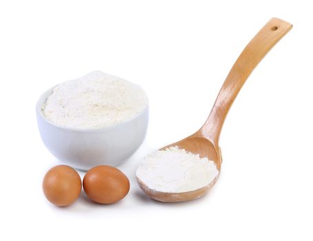 Spoon and bowl with flour, two brown eggs