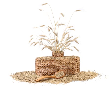 Wicker vase with ears of wheat, wheat grains, wooden spoon