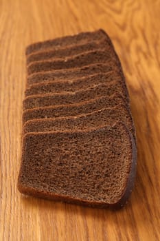 Slices of brown bread on a wooden table. Vertically.
