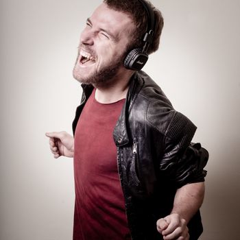 stylish hipster listening to music on gray background