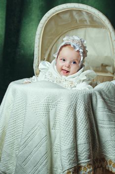 Cheerful and happy blue-eyed baby in  bonnet lies in cradle