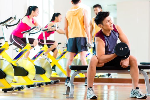 Chinese Asian group of men and woman doing sport exercise or training in fitness gym with barbell weights for more power