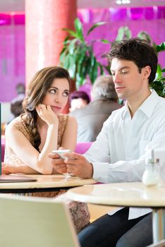 Couple in a cafe spends leisure time together, she is angry because he acts busy on the phone