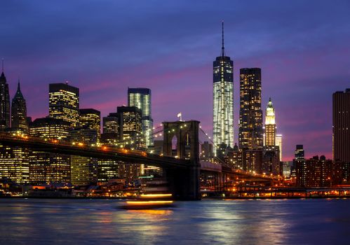 Brooklyn Bridge, East River and Manhattan at night with lights and reflections. New York City