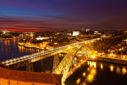 Panorama of lighted famous bridge Ponte dom Luis above Old town Porto and river Duoro at night, Portugal