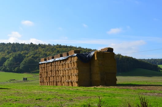 Large stack of hay made with many hay bales.