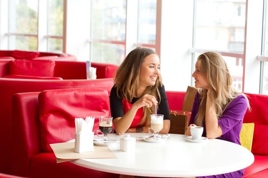 two girls drinking coffee in a cafeteria