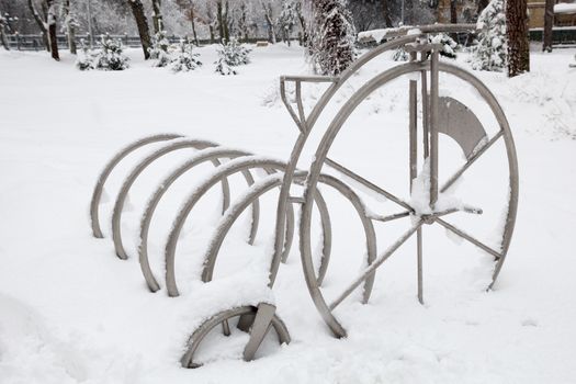 Snow in the city park. Snow covered  bicycle stand.