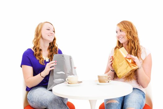 happy redhead women sitting at a coffee table with shopping bags on white background