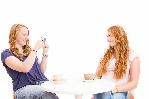 redhead woman making photos of her happy friend on white background