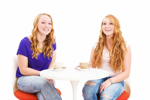 two laughing redhead women sitting at a coffee table on white background