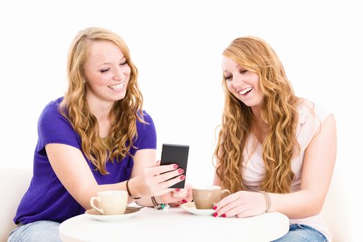 happy women looking at a smartphone sitting at a coffee table on white background