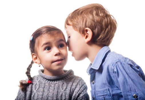 Boy whispering to a girl on white background.