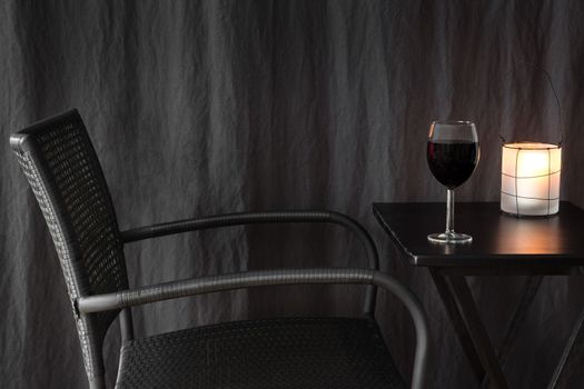 Cozy lantern decorating a table with glass of red wine.