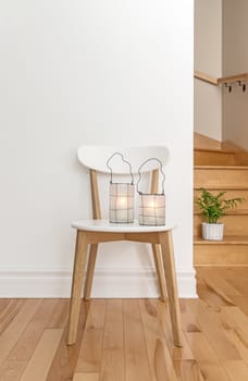 Lanterns on a white chair, in a room with staircase.